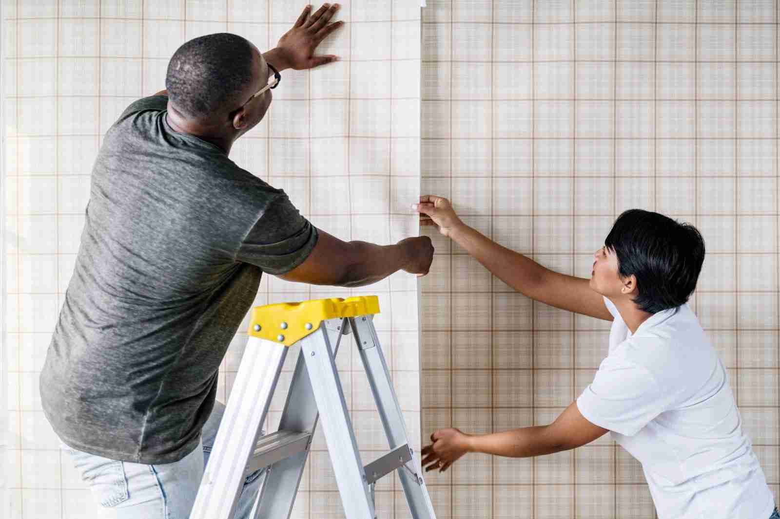 A couple applying wallpaper in a new Airbnb