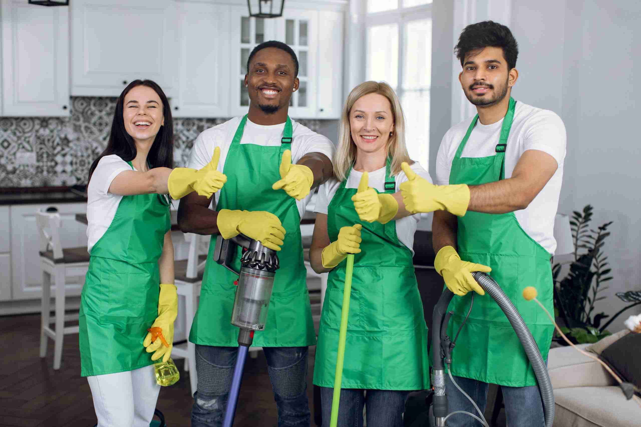 Smilteam of professional cleaners showing thumbs up to camera