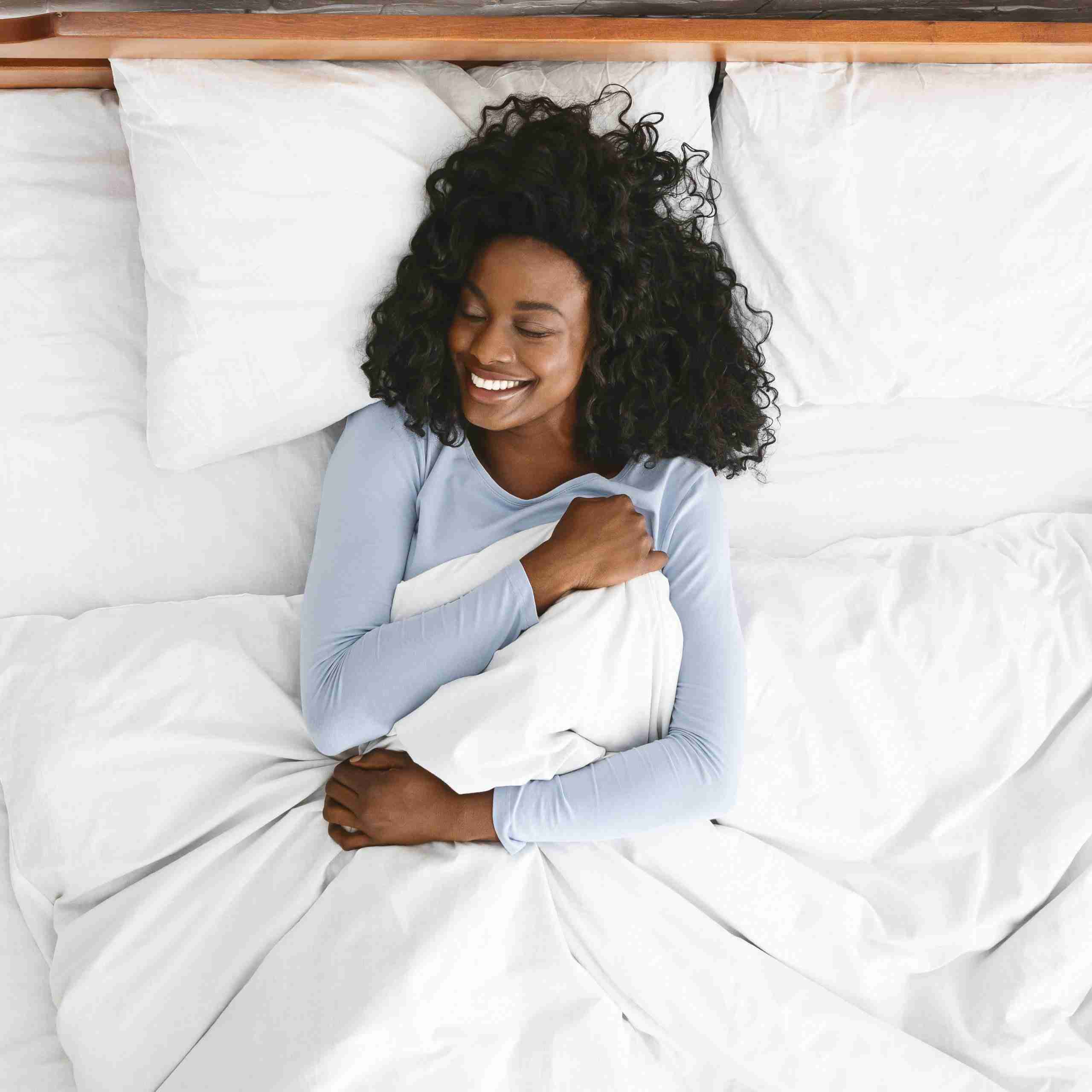 Woman laying on a bed in clean white sheets